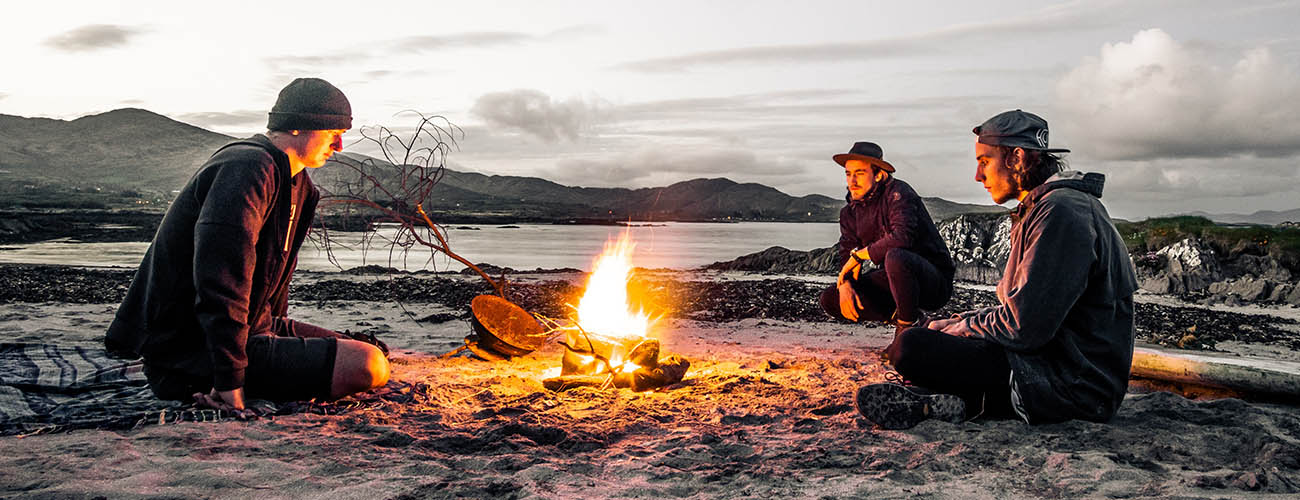 trois jeunes gens sur une plage irlandaise devant un feu de camp