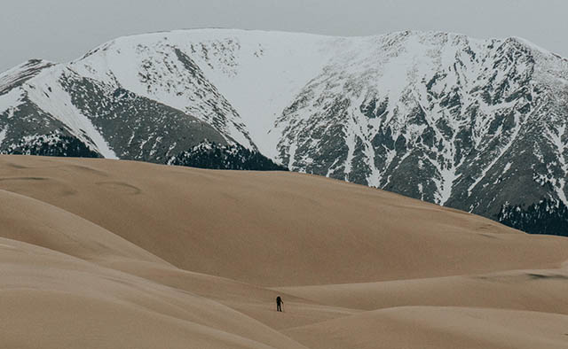 randonneur dans un immense paysage de sable et de roche enneigé