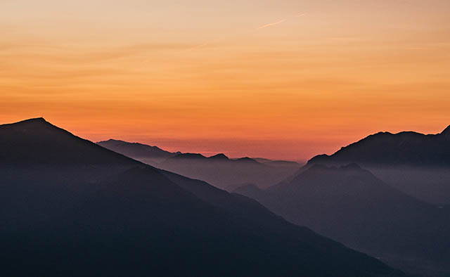 ciel orange et sommet de montagnes bleu sombre